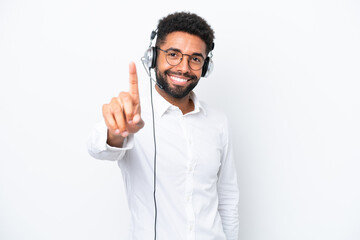 Telemarketer Brazilian man working with a headset isolated on white background showing and lifting a finger