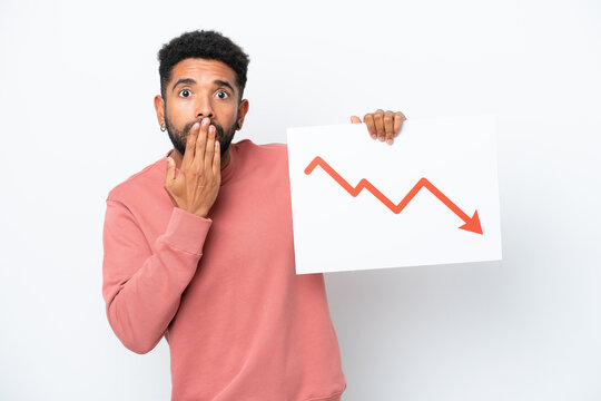 Young Brazilian man isolated on white background holding a sign with a decreasing statistics arrow symbol with surprised expression