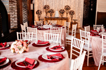 a round table decorated with a flower arrangement, glass bowls, plates and red napkins