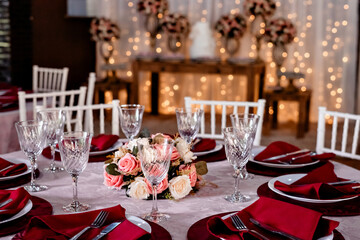 a round table decorated with a flower arrangement, glass bowls, plates and red napkins