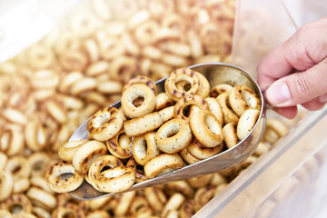 Woman buyer in shop buys bagels using scoop