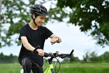 Naklejka premium Satisfied male cyclist checking his workout progress on a smart watch