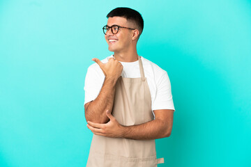 Restaurant waiter man over isolated blue background pointing to the side to present a product
