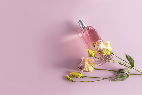 An elegant bottle of eau de parfum or cosmetic spray on a pastel background with spring austoma flowers. Top view. space for text.