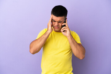 Naklejka premium Young handsome man using mobile phone over isolated purple background with headache