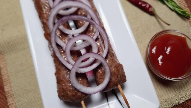 Baked lula kebab on rectangular dish on a rustic table