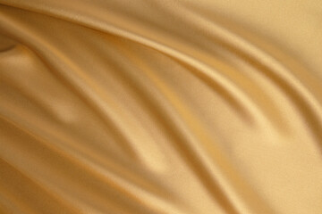 Abstract gold satin background of luxurious fabric. soft gentle waves of fabric. The golden texture...