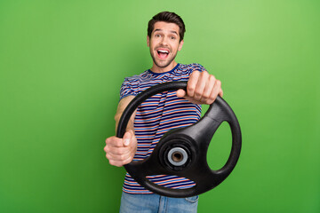 Photo of young funny overjoyed driver automobile guy holding steering wheel crazy surprised high speed isolated on green color background