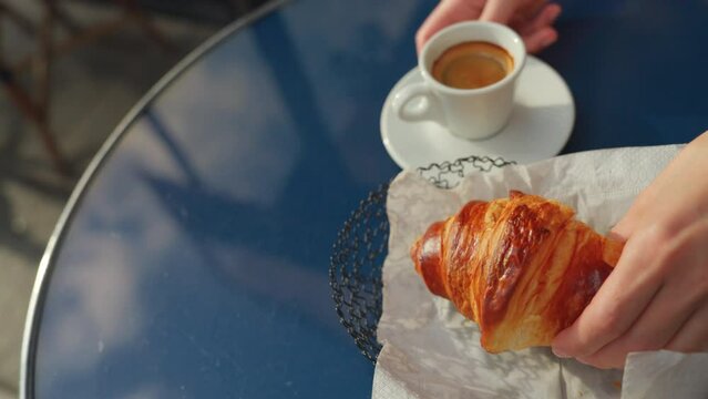 White cup of coffee and a croissant on a blue table in a restaurant