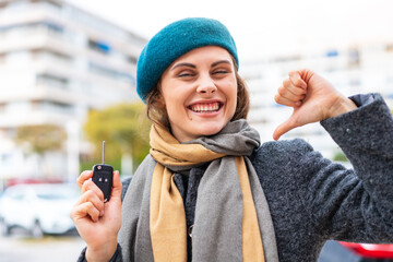 Brunette woman holding car keys at outdoors proud and self-satisfied