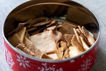 A portrait of a round tin can with christmas prints on it, with home made cookies inside of it. The tasty unhealthy holiday treat is simple to bake and a great snack.