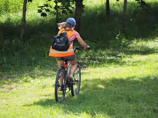 A woman with a backpack rides a bicycle in the park. Active recreation - bicycle tourism. Lifestyle and pastime