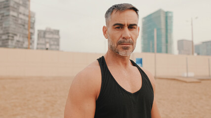 Fototapeta premium Middle aged athletic man posing for camera while standing on the beach