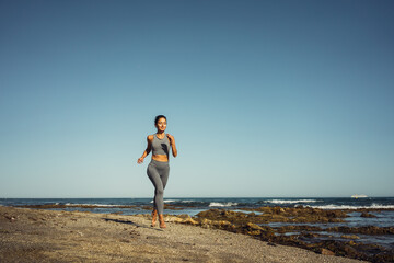a beautiful brunette girl in gray leggings is engaged in fitness on the sand against the background of the sea