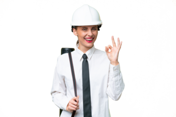 Young architect woman with helmet and holding blueprints over isolated background showing ok sign with fingers