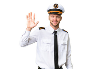 Airplane pilot man over isolated background saluting with hand with happy expression