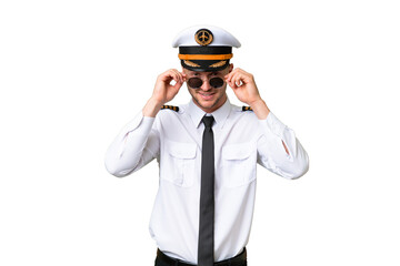 Airplane pilot man over isolated background with glasses and surprised