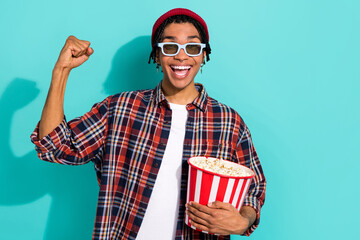 Photo portrait of attractive young male raise fist excited premiere wear trendy plaid garment isolated on aquamarine color background