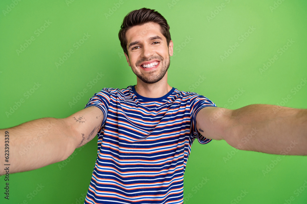 Sticker Selfie photo of friendly young blogger man wear stylish t-shirt recording his memories video portrait isolated on green color background