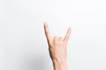 A man's hand in close-up shows a rock or punk gesture on a white background.