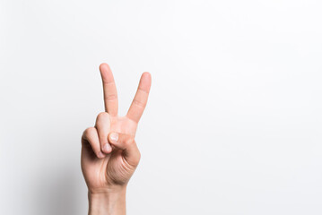 Close-up of a man's hand showing gesture number two or victory on a white background. - Powered by Adobe