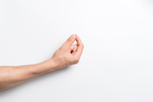 Close-up of a man's hand holding with his fingers an invisible object or item for a copy space with an advertisement on a white background.