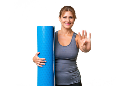 Middle-aged sport woman going to yoga classes while holding a mat over isolated background happy and counting four with fingers