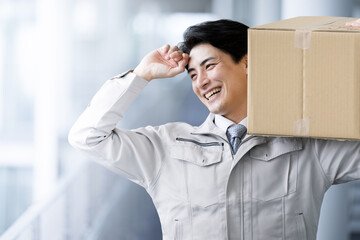 Also for the main visual! Handsome or smiling Asian (Japanese) worker carrying a cardboard box. For...