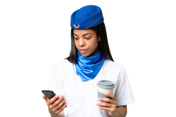 Airplane stewardess African american woman over isolated background holding coffee to take away and a mobile