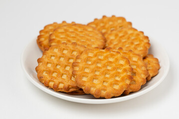 Curly shortbread biscuits in white plate isolated on white background