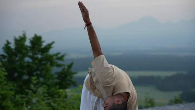 Man stretching and doing yoga pose on top of the hill at sunrise at sunrise
