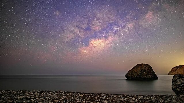 Timelapse of the milky way and the stars on a coast with rocks at night. wide angle