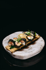 Sushi Mansa Maki decorated with microgreens on a black background