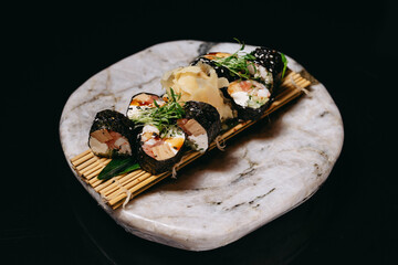 Sushi Mansa Maki on a stone tray on a black background