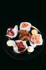 Assorted snacks for beer on the black plate