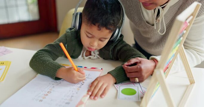 Education, writing and mother with son in a kitchen for distance learning, maths and headphones for autism. Special needs, tutor or remote learning for autistic kid with mom for help, support or care