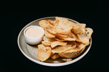 Fried croutons with sour cream sauce on a black background