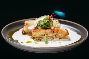 Lasagna with creamy sauce on a grey plate