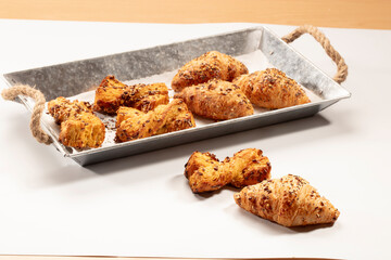 Cruasán y lazos, dulces sobre una fuente y en la mesa. Croissant and bows, sweets on a platter and on the table.