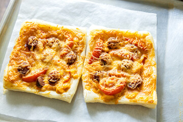 Top view of jus cooked hot pieces of pizza on the bakeware pan and paper. Homemade pizza