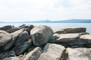 Landscape view of lake Turgoyak in summer with boulders in the foreground, South Ural, Russian Federation