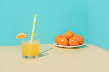 Glass of fresh orange juice on beige table. Blue background.