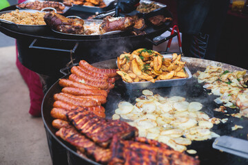 Food festival with food stall kiosk, open-air outdoor fair market, assortment of different traditional European grilled barbecued street food with sausages, bbq, chicken, pork and lamb on a large pan - obrazy, fototapety, plakaty