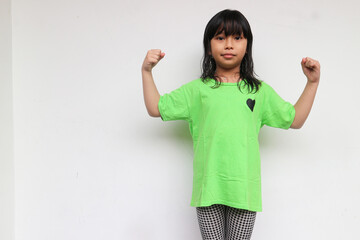 Power girl. A cute confident girl looking at camera raised hand showing her bicep muscle