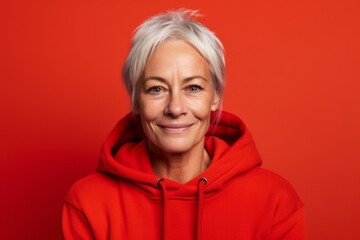 Lifestyle portrait photography of a satisfied mature woman wearing a comfortable hoodie against a red background. With generative AI technology