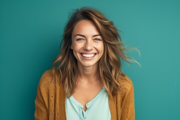 Close-up portrait photography of a happy girl in her 30s wearing a chic cardigan against a turquoise blue background. With generative AI technology