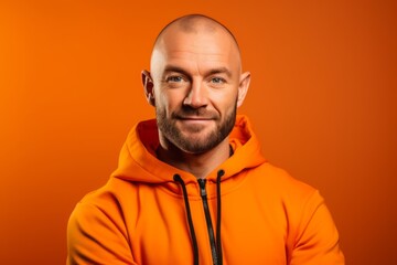 Obraz premium Headshot portrait photography of a glad boy in his 30s wearing a comfortable tracksuit against a bright orange background. With generative AI technology