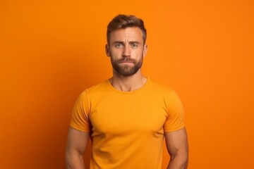 Medium shot portrait photography of a beautiful boy in his 30s wearing a casual t-shirt against a bright orange background. With generative AI technology