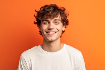 Close-up portrait photography of a satisfied boy in his 20s wearing a casual t-shirt against a bright orange background. With generative AI technology