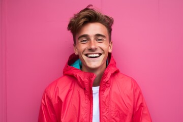 Obraz premium Medium shot portrait photography of a grinning boy in his 30s wearing a lightweight windbreaker against a hot pink background. With generative AI technology